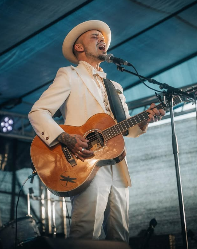 Dan Viktor på scen i vit kostym med gitarr